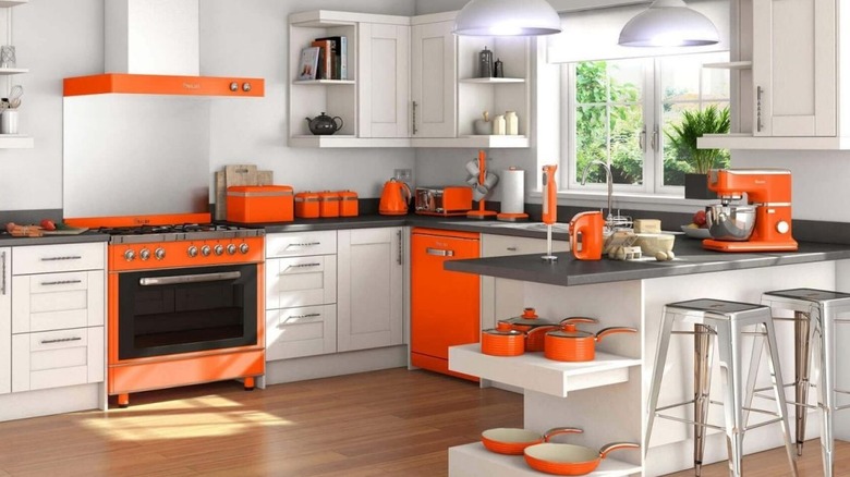 Photo of a modern white kitchen with orange appliances