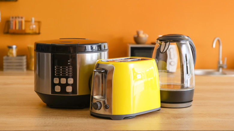 Yellow toaster and other kitchen appliances against an orange wall