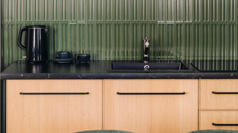 A kitchen with wood cabinets and black countertops