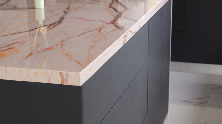 The corner of a peach-toned marble countertop in a gray kitchen