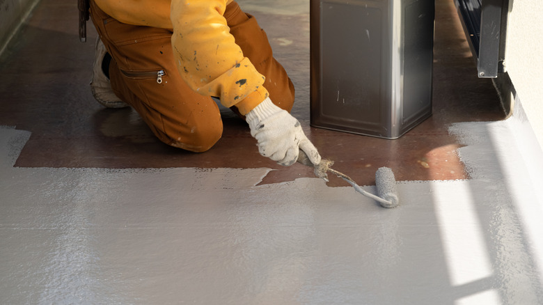 person painting floor with a roller