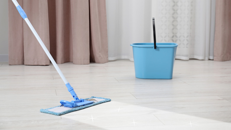 a mop bucket and wet mop being used to mop floor