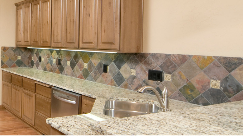 A kitchen with a granite countertop and colorful backsplash