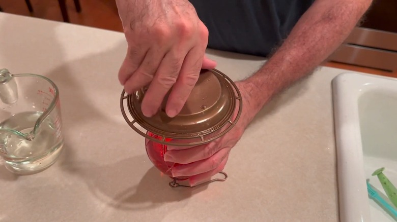 Putting together a hummingbird feeder with visible water droplets on top