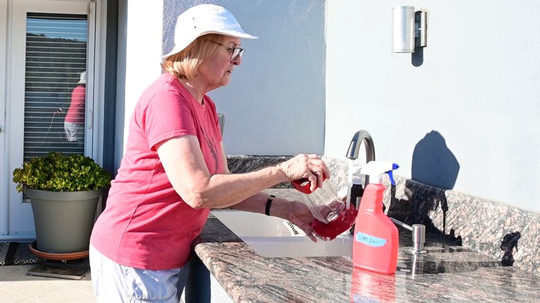 Woman rinsing a hummingbird feeder in outdoor sink