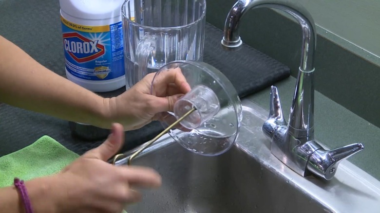 Woman washing hummingbird feeder with a bleach and water solution