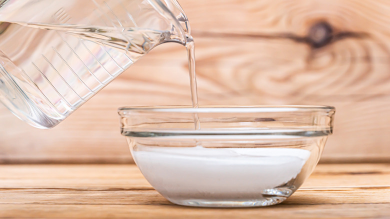 A container of water poured over a bowl of sugar