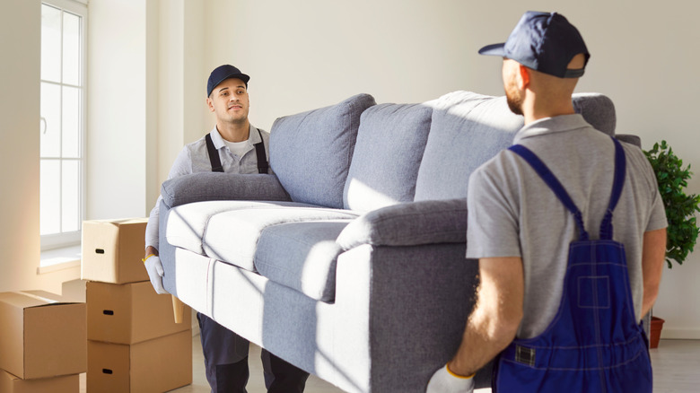 Two people moving a couch into a home