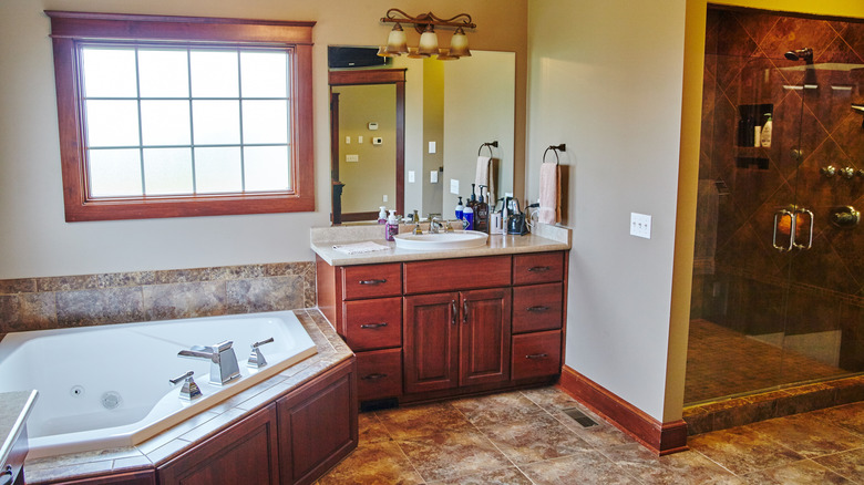 A bathroom with cherry wood cabinetry and corner tub