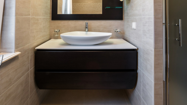 A vanity and sink with dark wood finish