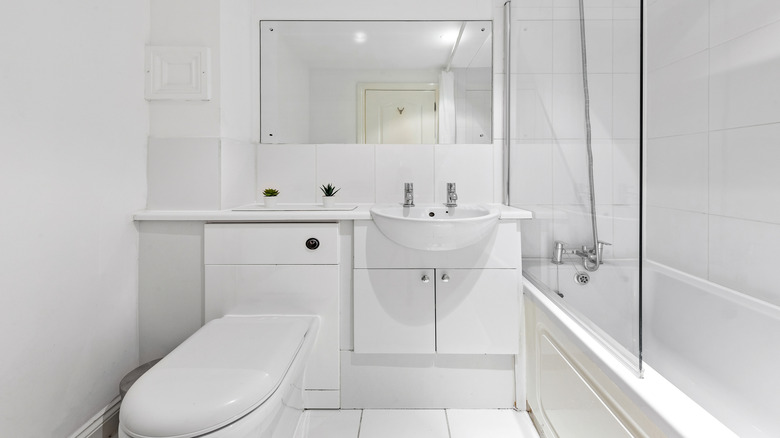 A bathroom with all white cabinets and tiling