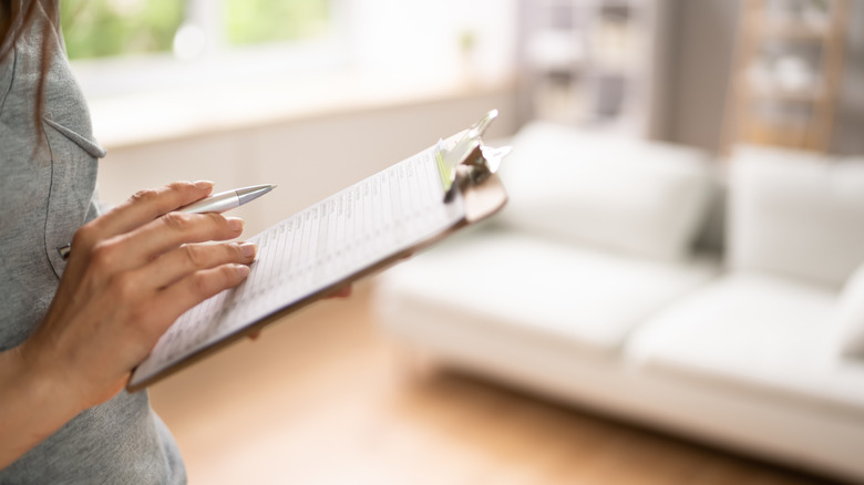 woman holding clipboard taking notes inside home