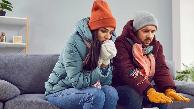 Couple sitting on couch wearing coats