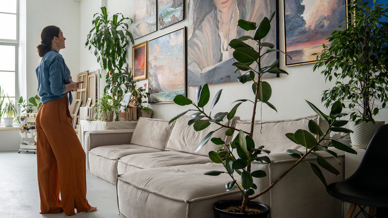 woman standing in living room admiring large artwork gallery wall