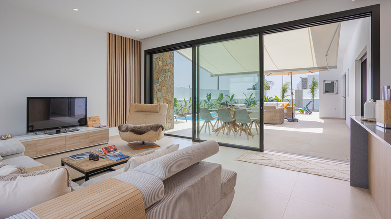 Living room with sliding glass doors opening to terrace with pool and dining area.