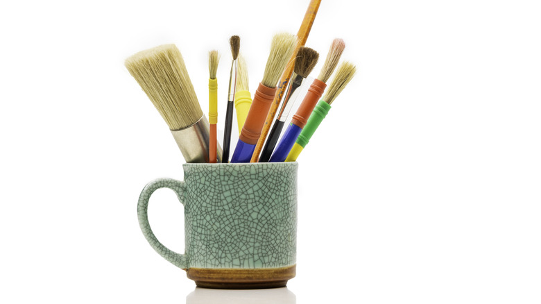 A coffee mug holding paintbrushes