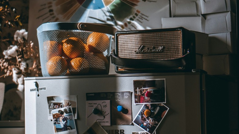 Oranges on top of a fridge in a wire basket