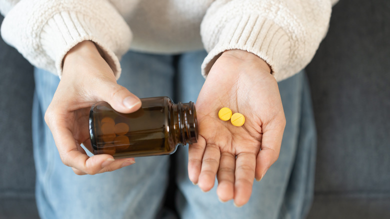 Woman holding medication from prescription bottle