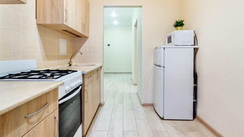 Microwave on top of a small white refrigerator