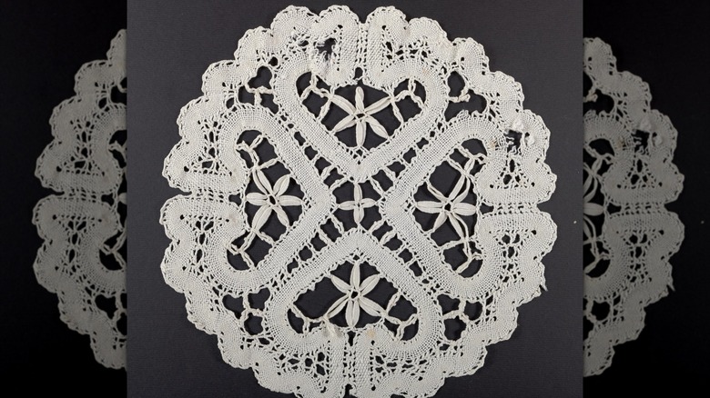 A large Battenberg lace doily on a gray background.