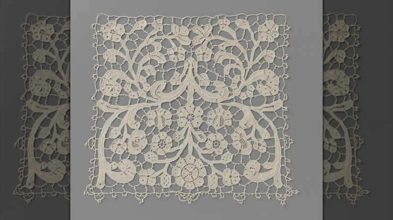 A square doily of Venetian needlepoint lace.
