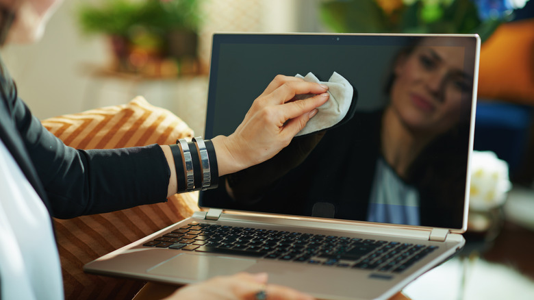 Woman wiping laptop screen