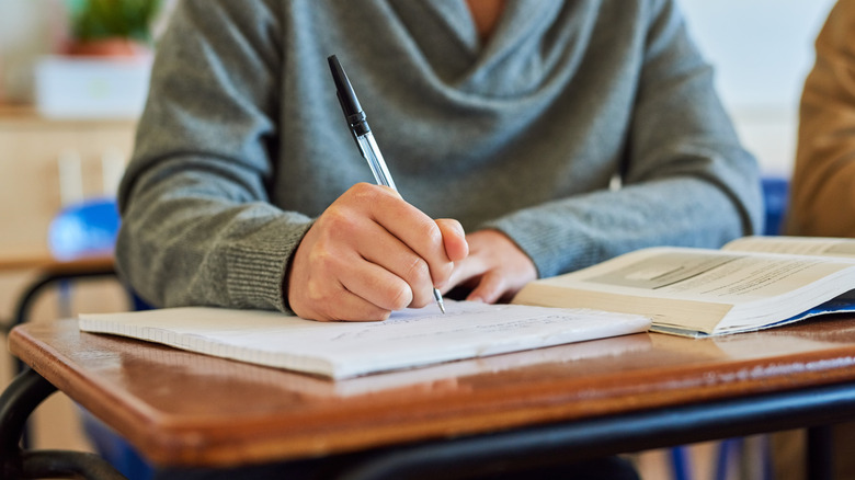 Student scribbling in a notebook in an education setting