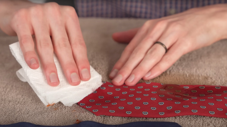woman's hands gently scrubbing red patterned silk tie