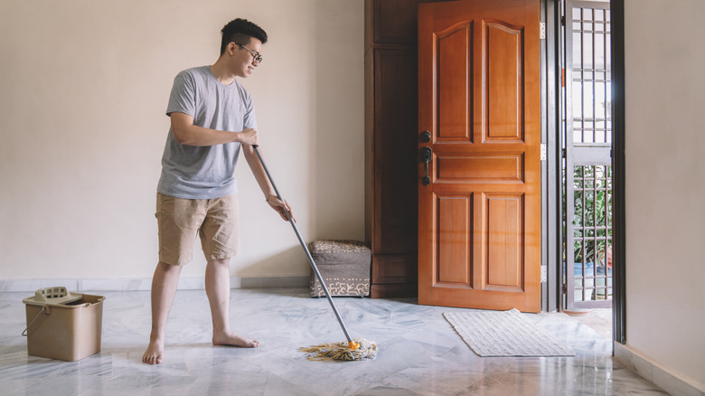 young man mopping white marble floor