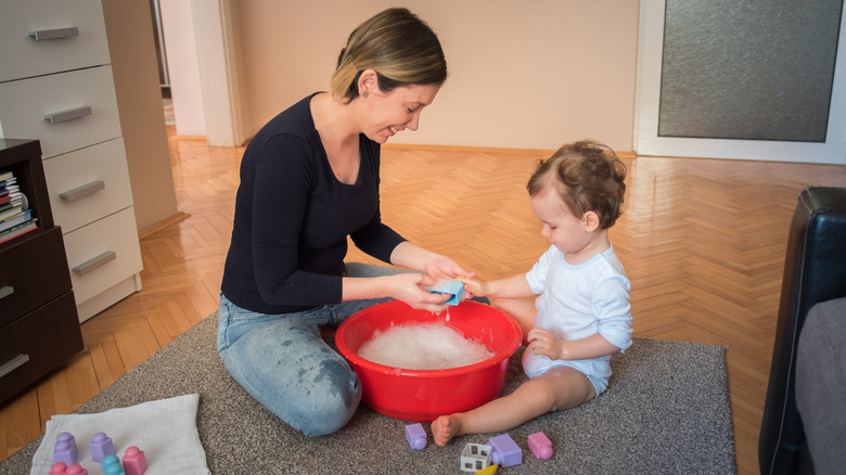 young mother washing toys with toddler