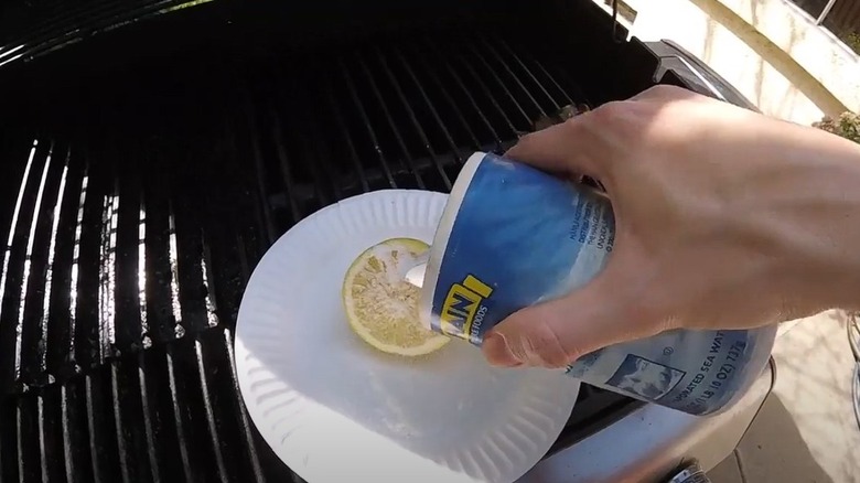 a man cleaning outdoor grill grates with salt and lemon