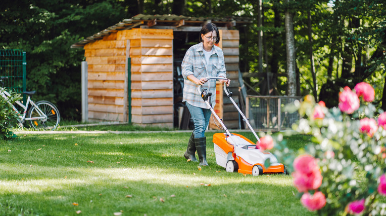 Woman mowing a shady area of the lawn