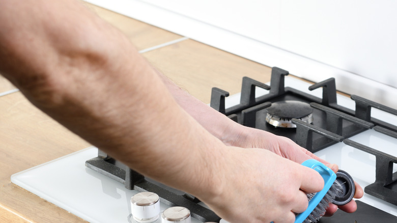 Man scrubbing stove top parts with brush