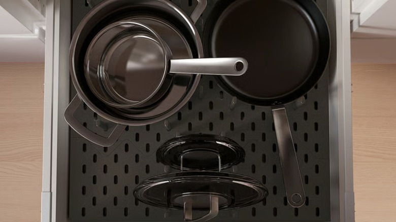 Stainless steel and cast iron pans in pegboard drawer