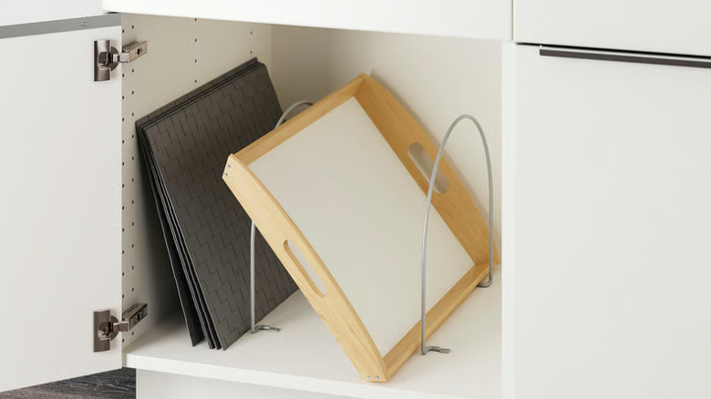 Kitchen platters and sheets tucked in partitions in cabinet