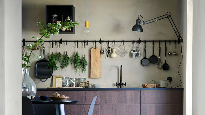 Long kitchen wall rail with hanging cooking utensils and pans
