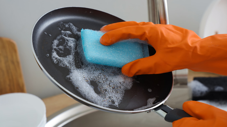 Person handwashing a pan in a kitchen sink
