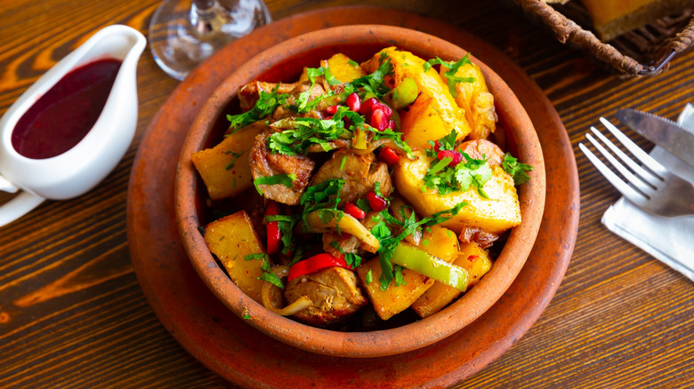 A clay pan full of potatoes and herbs.