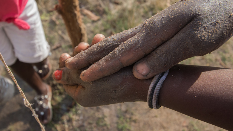 someone rubbing ash on their hands to wash them