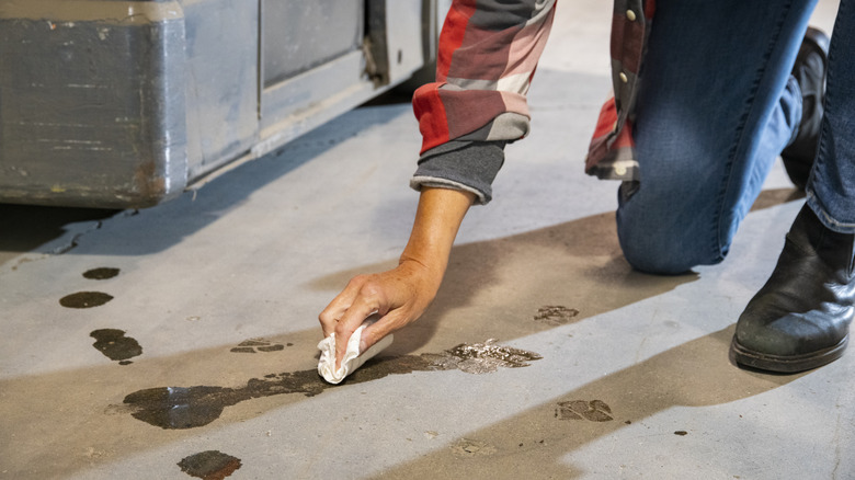 someone cleaning up oil spill on concrete floor