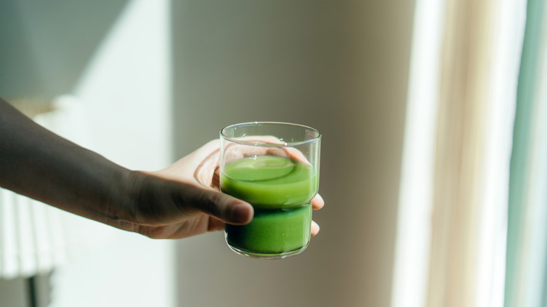 Woman holding glass of green juice