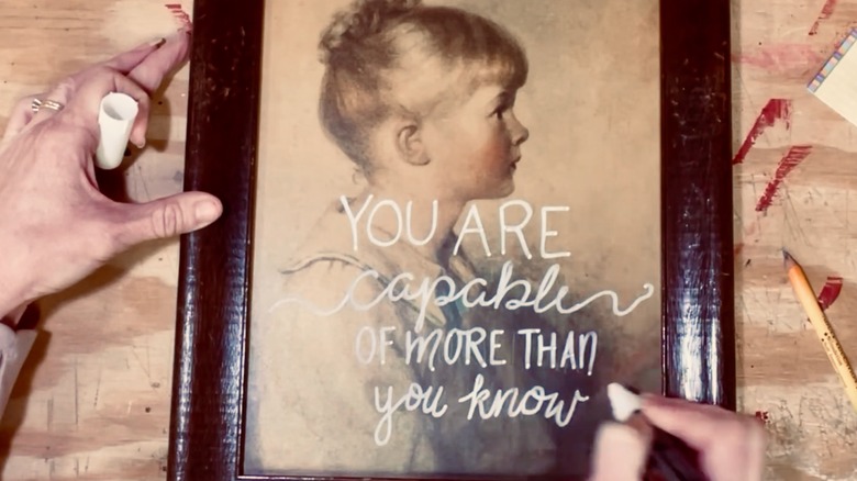 DIYer uses a chalk-paint pen to write inspiring words on a a vintage print
