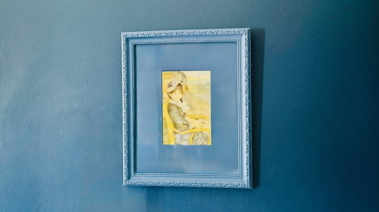 A color-drenched picture frame and mat hang on a similarly colored wall.