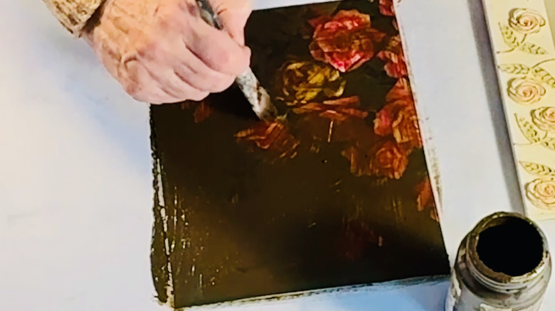 Crafter paints waterbased antiquing wax over art print.