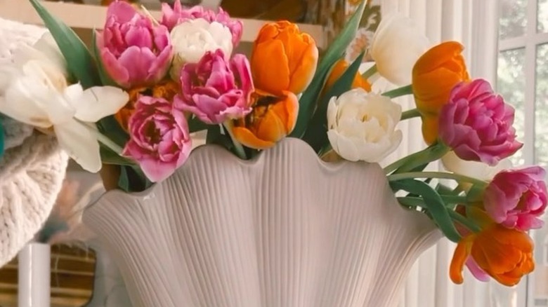 white, pink, and orange double tulips in a scalloped vase