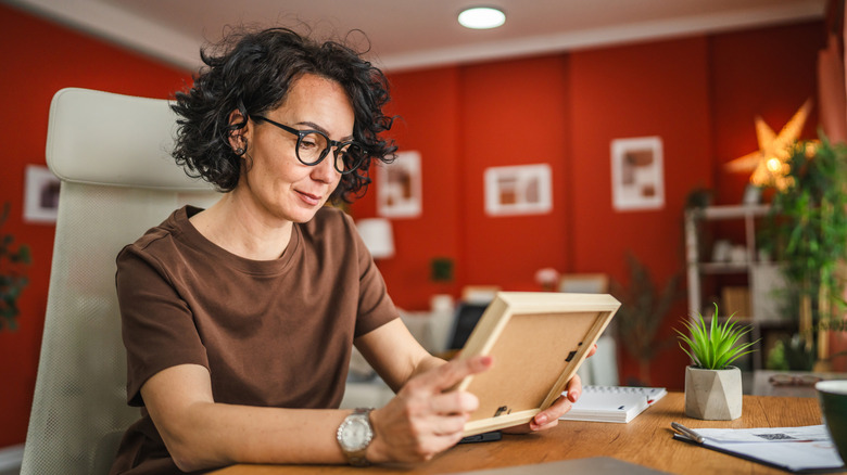 Woman admiring photo in frame at home office desk