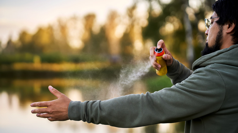 Adult man spraying long sleeve shirt with tick spray