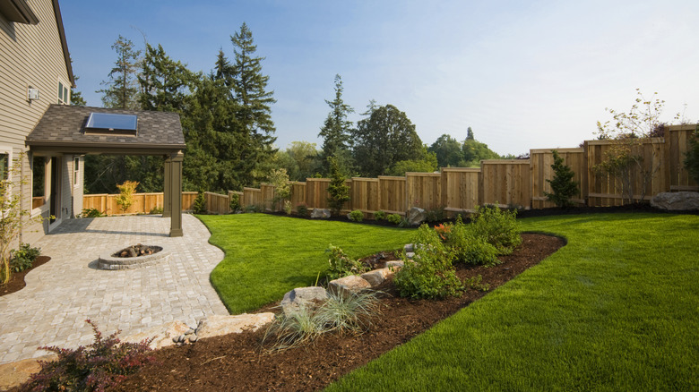Well manicured lawn with mulch, sparse plants, and pavers