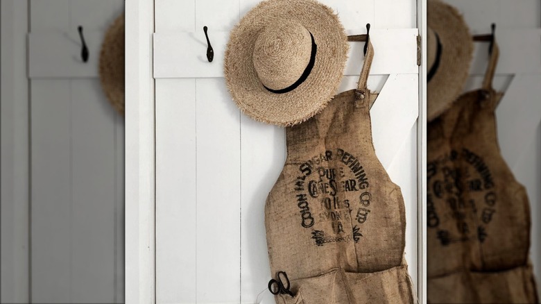 burlap apron and woven wide-brimmed hat hanging on door