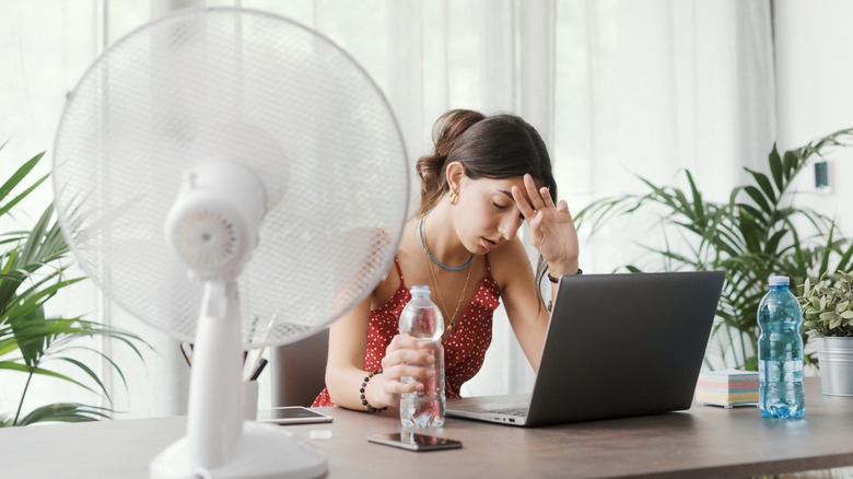 Young woman trying to stay cool in office during heat wave